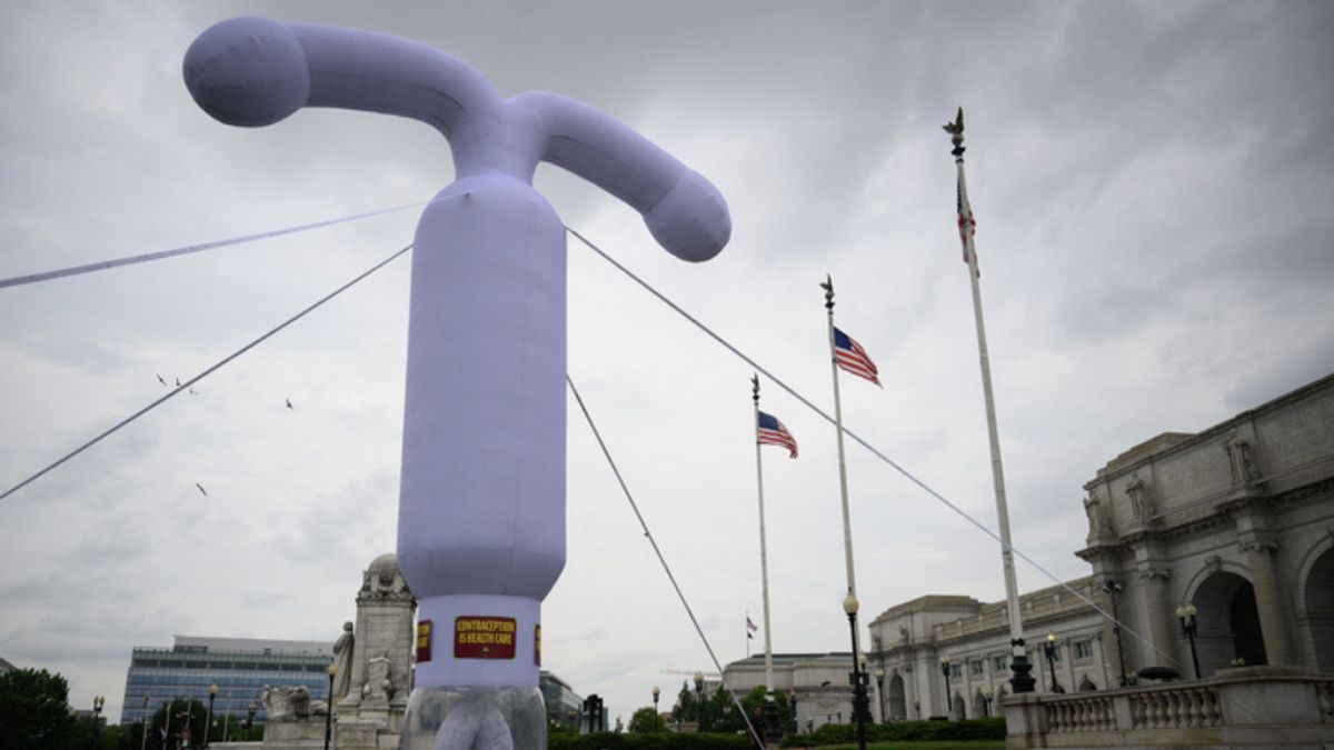 A giant purple blowup intrauterine device, or IUD, on a lawn. 