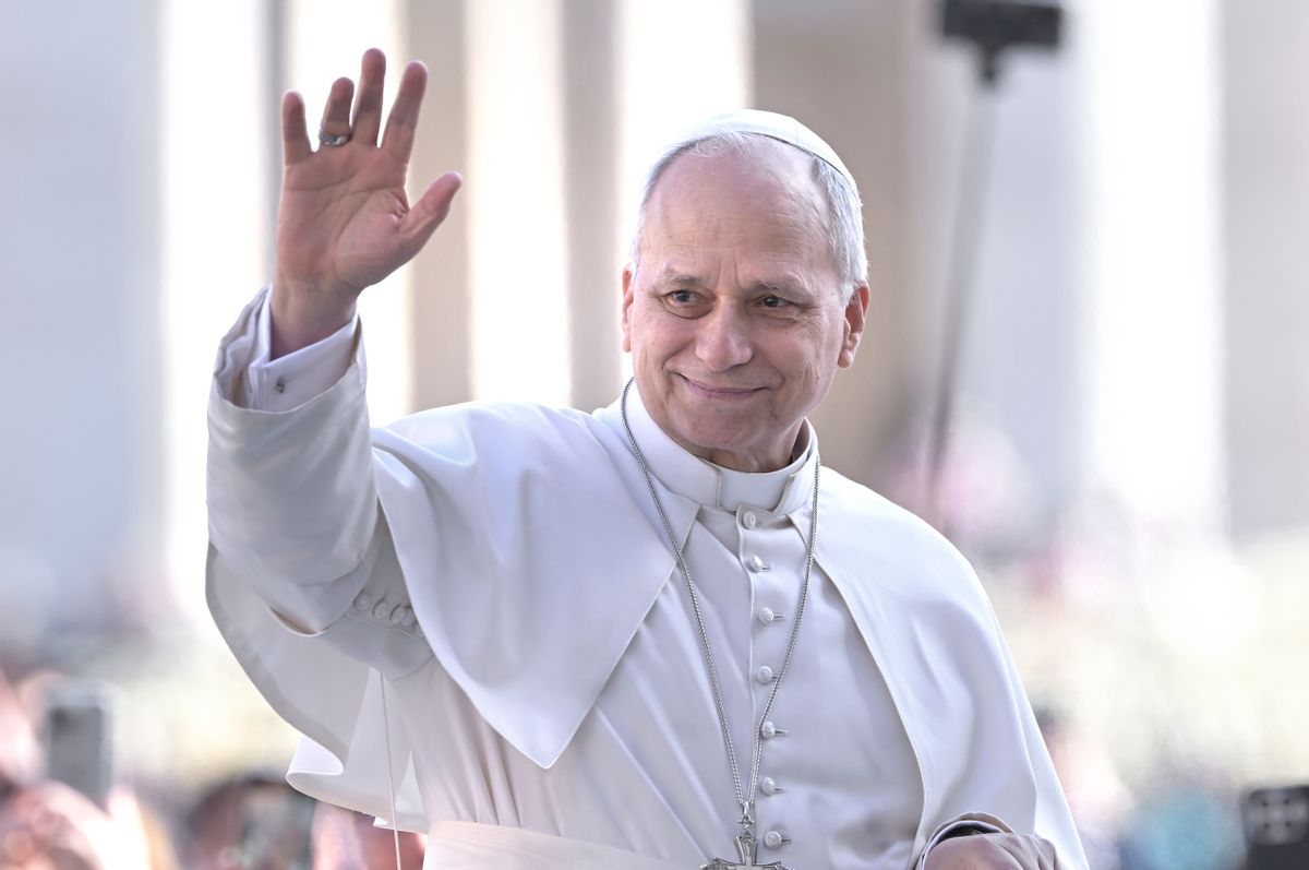 Pope Leo, an elderly white man, wears the traditional all-white outfit and papal frock and waves to a crowd.