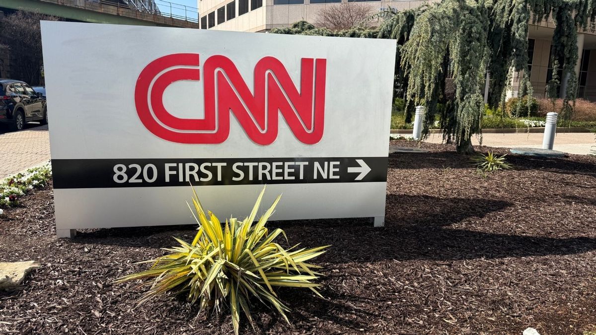 An image shows a photo of a low-height CNN sign, with CNN in red letters, with 820 First Street NE as the address also displayed on the same sign, surrounded by mulch, plants and tan buildings.