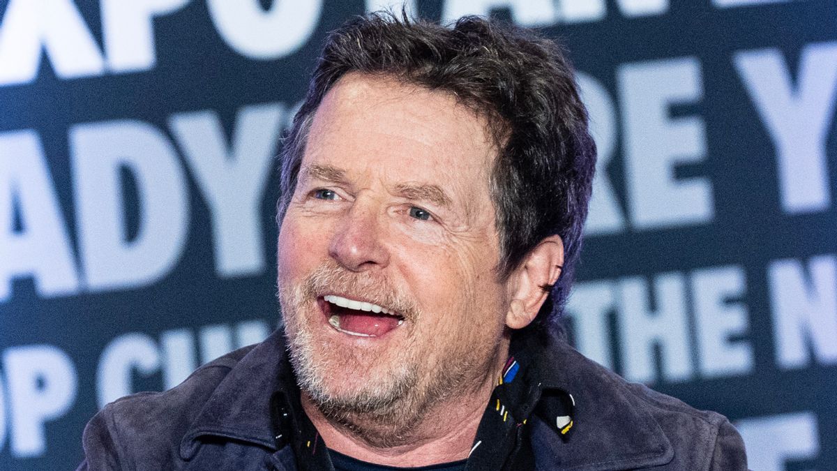 Actor Michael J. Fox, a white man, is pictured smiling in front of a background featuring various words.