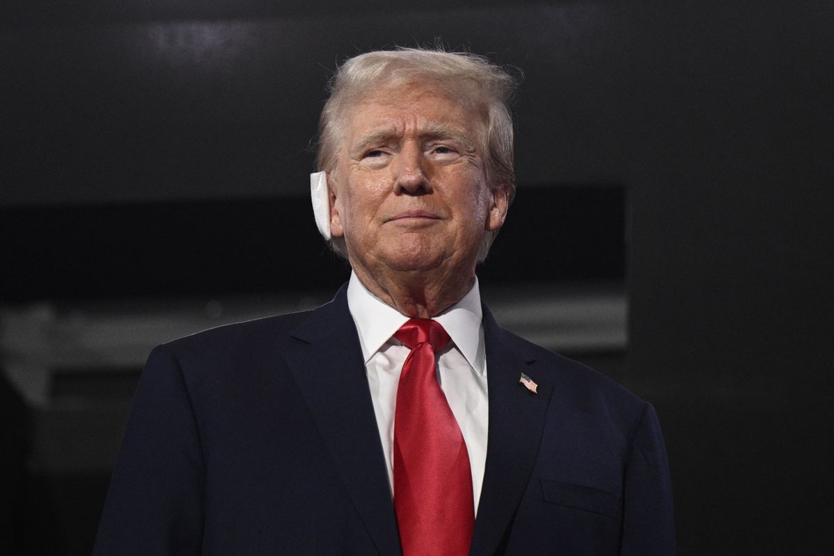 Image shows president candidate Donald Trump standing with a bandage on his ear.