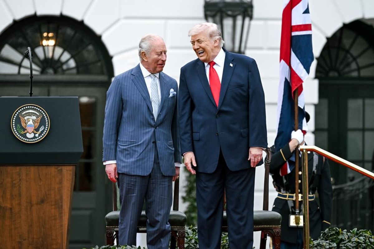 U.S. President Donald Trump and King Charles III stand together laughing. 