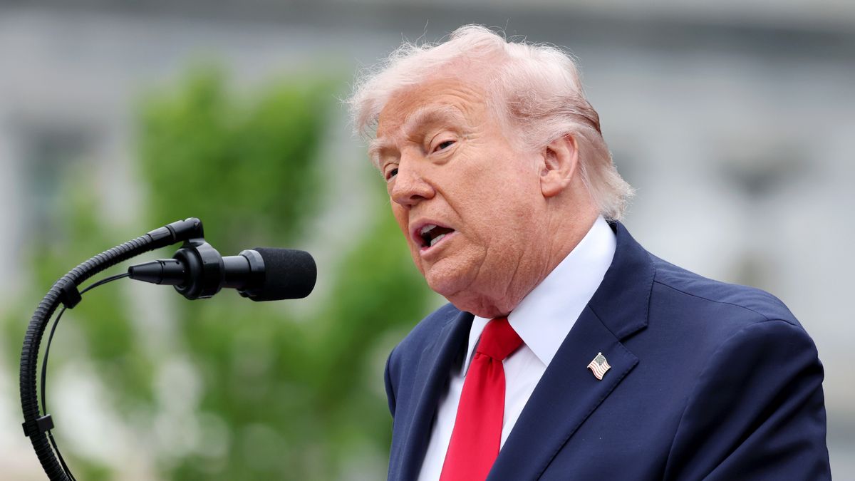 U.S. President Donald Trump, an older white man with pale blond hair, in front of a curved microphone. 