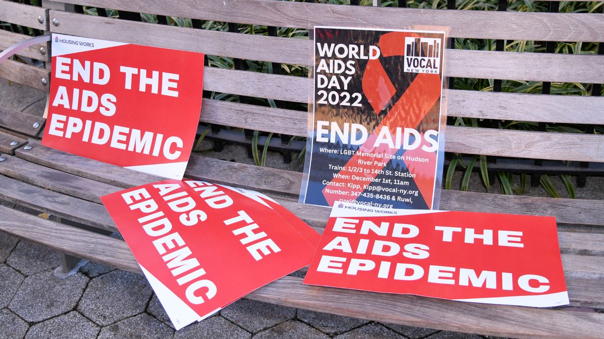 Red posters that say, "END THE AIDS EPIDEMIC" scattered on a bench. 