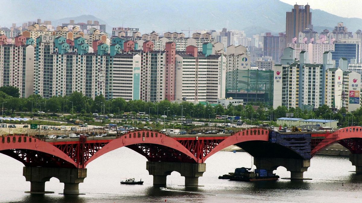 Buildings are pictured near a bridge. Boats can be seen passing underneath the bridge.