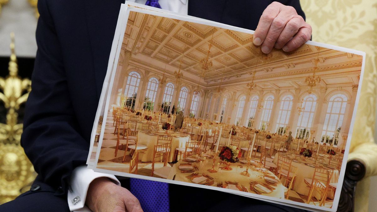 Close-up shot of U.S. President Donald Trump's hand holding up a piece of paper showing mockups for the interior of a golden ballroom. 