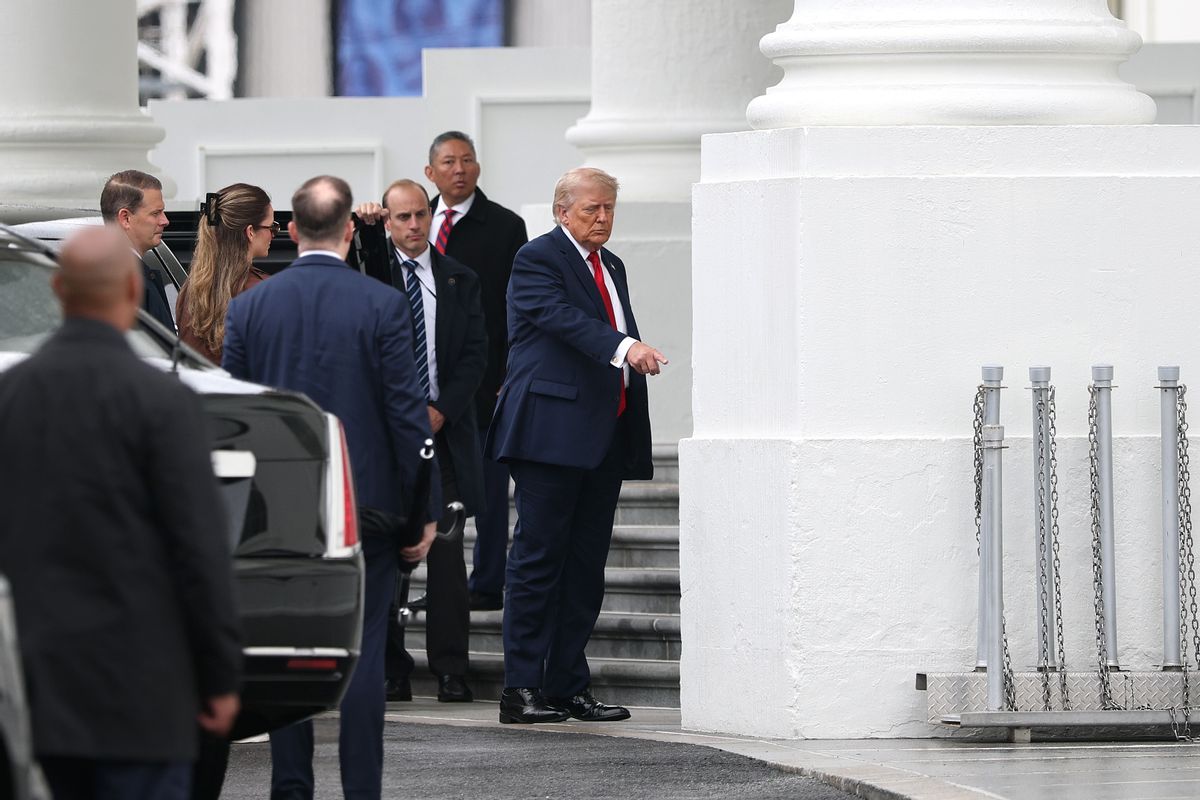 Image shows President Donald Trump pointing to a White House column. 