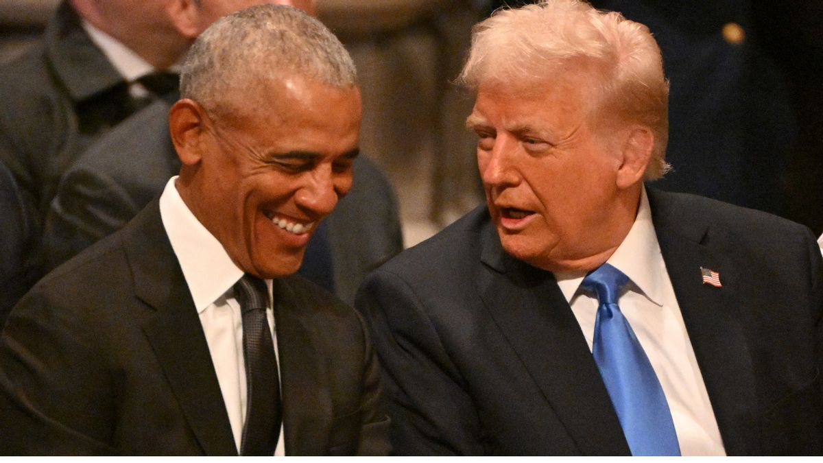 Barack Obama and Donald Trump, both wearing suits, sit next to each other. Obama appears to be laughing at something Trump said.