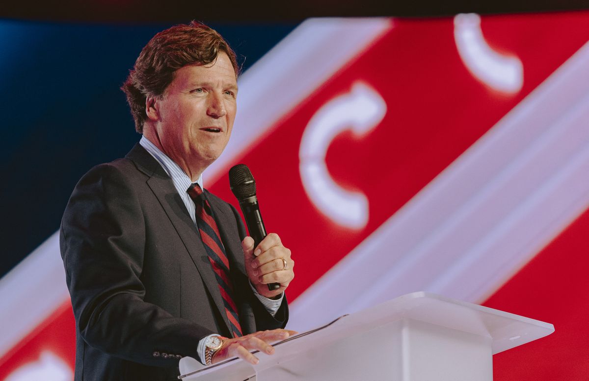 Image shows Tucker Carlson speaking at an event. 