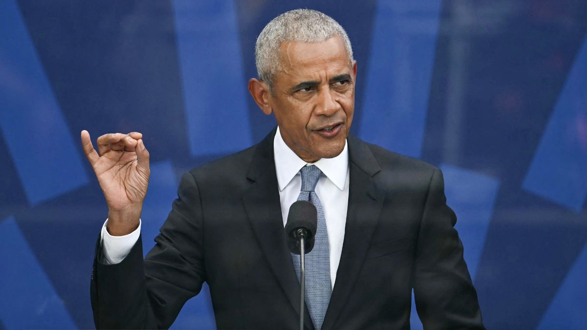 Former President Barack Obama stands in front of a podium. 