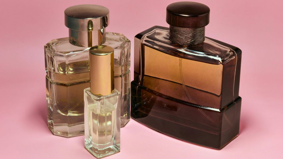 Several glass bottles of perfume are displayed against a pink background.