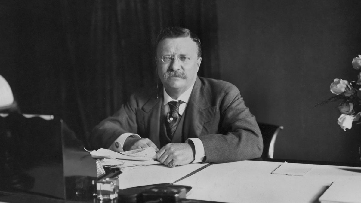Image shows Theodore Roosevelt seated at a desk.