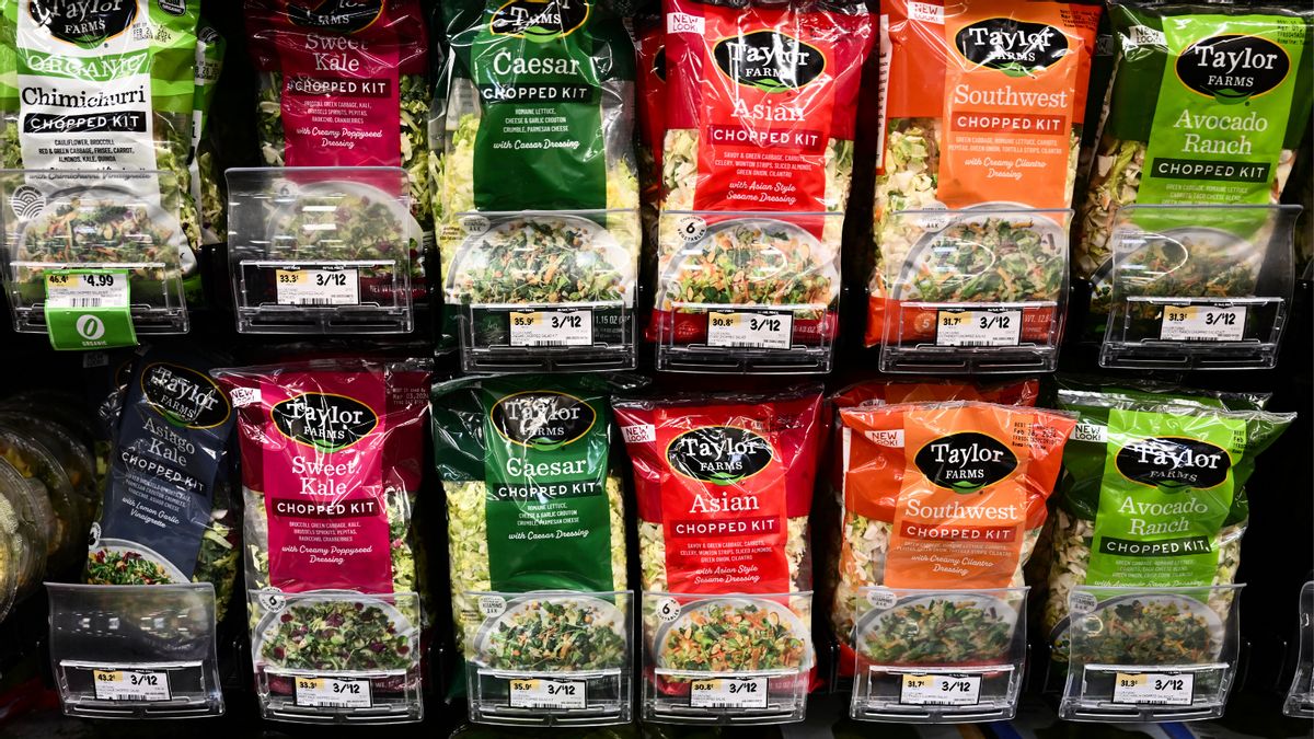 Rows of Taylor Farms-branded salad kits in the produce aisle of a grocery store. 