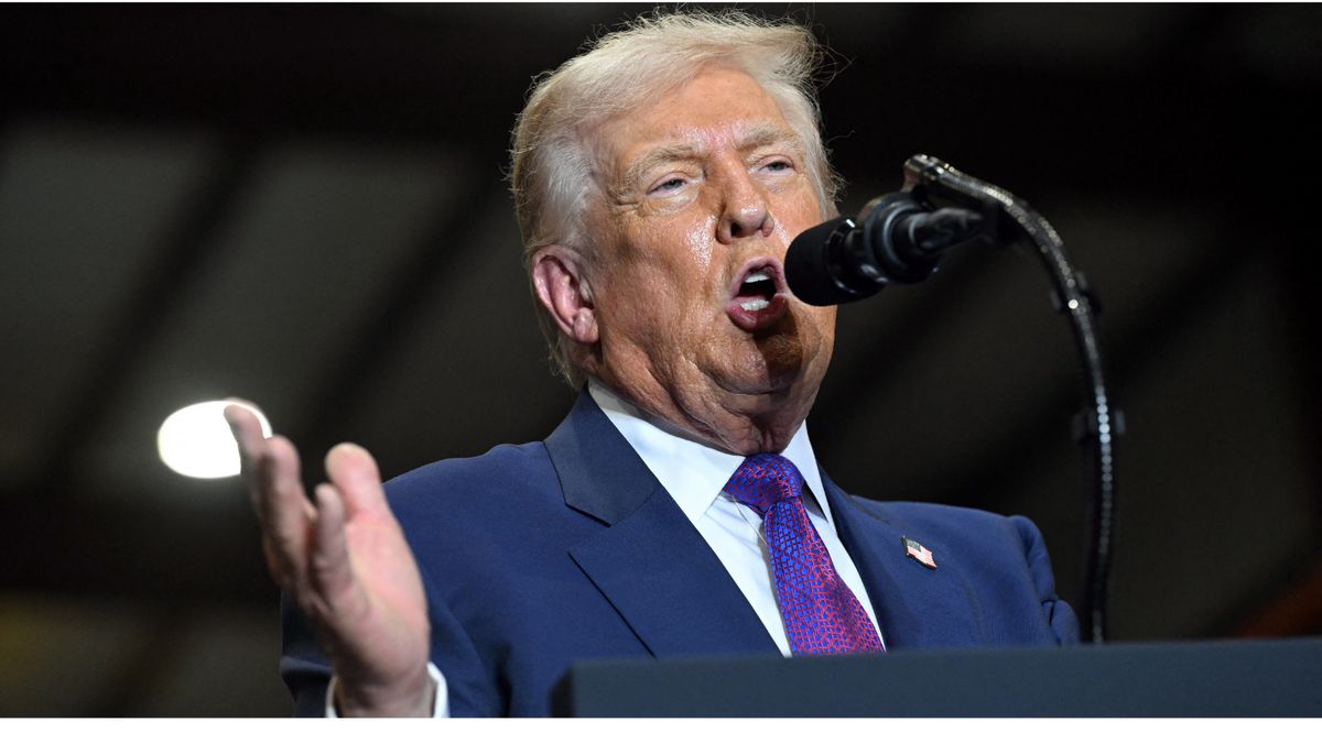 President Donald Trump, an older white man with light hair, wears a blue suit jacket and multicolored tie while speaking into a microphone.