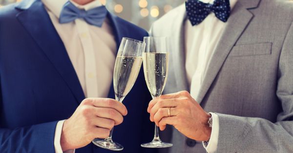 Two men in tuxedos drinking champagne