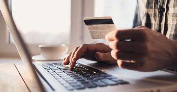 Man holding credit card in front of laptop computer