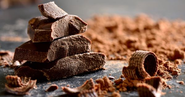 Stack of dark chocolate with chocolate chips and cocoa powder.