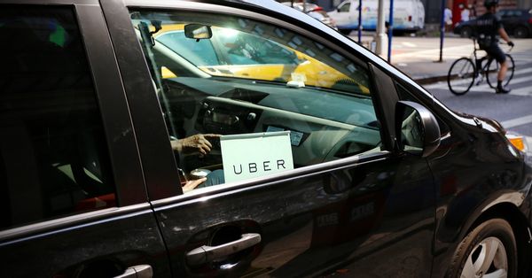 A black car with an "Uber" sign in the passenger side window.