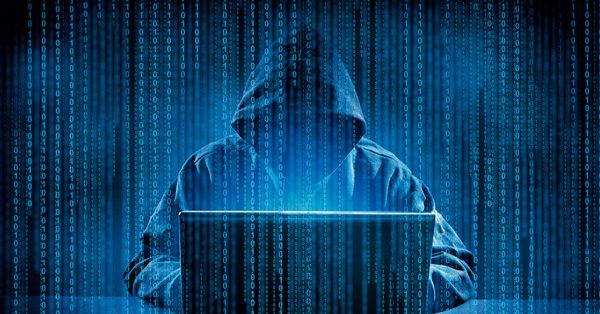 Person wearing a hoodie sits in front of a laptop computer