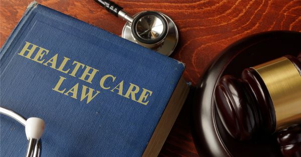 Book titled "Health Care Law" next to a stethoscope on a table.