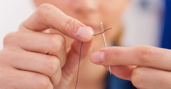 Close-up of someone threading a needle.