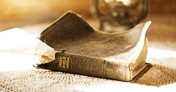 Old, torn-up Bible illuminated by a sunbeam