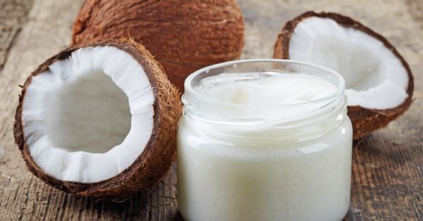 Coconuts next to a jar of coconut oil.