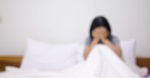 Blurred photograph of woman crying alone in bed.