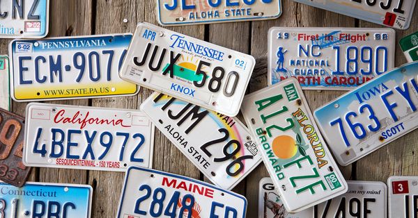 License plates from various U.S. states scattered across a flat wooden surface