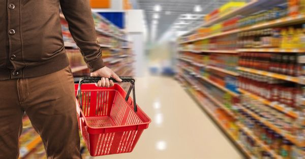 Hand holding grocery basket in store aisle
