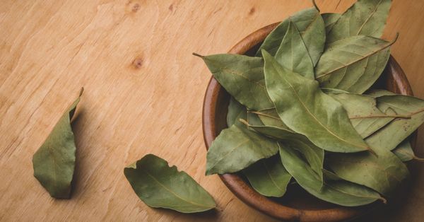 Bowl of bay leaves on wooden surface