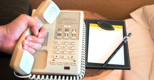 Person holding hotel phone receiver