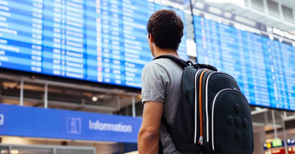 Man wearing backpack standing in front of an airport