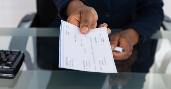 Paycheck being handed over across a desk