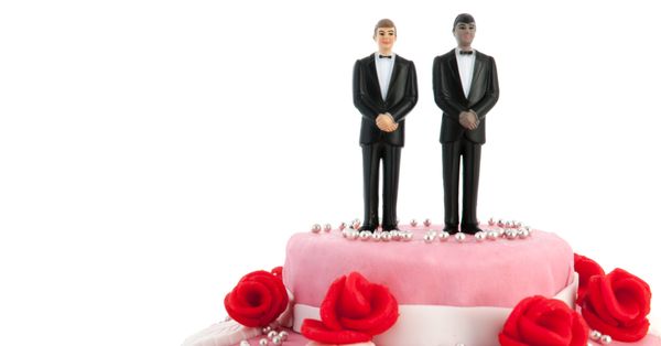 Wedding cake with figurines of two men in suits on top.