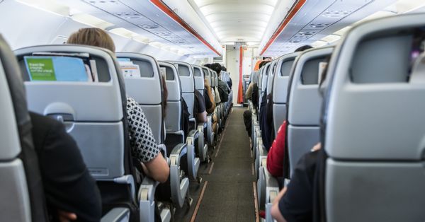 Aisle view of commercial airline interior with passengers.