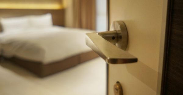 Hotel room door handle in focus with bed in background