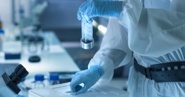 Scientist in hazmat suit holding a vial.