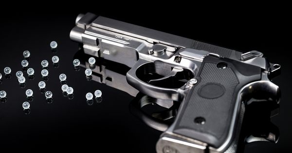 Airsoft gun surrounded by BB pellets.