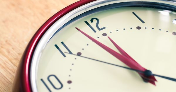 Analog clock face showing two minutes to midnight (or noon.)