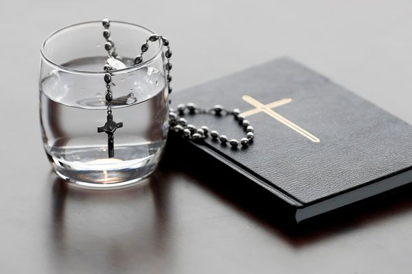 Rosary, glass of water, and holy Bible during Lent