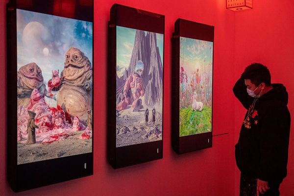 A man looks at digital paintings by US artist Beeple at a crypto art exhibition entitled Virtual Nich