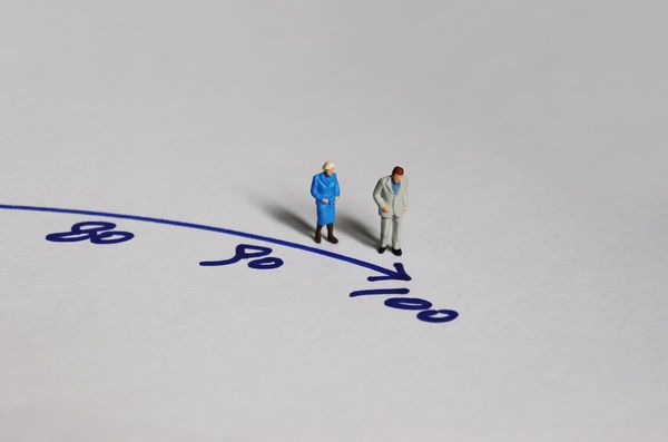 Old,Couple,Miniature,Standing,Before,The,Number,100.