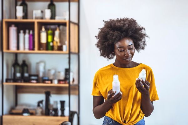 Photo of African american young woman examining some beauty products in a salon.