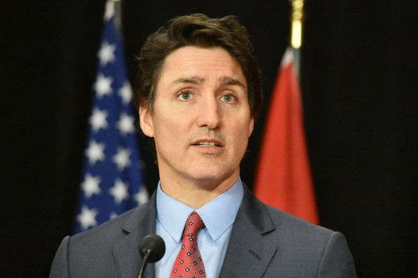 A white man in a gray suit speaks stands in front of a microphone.