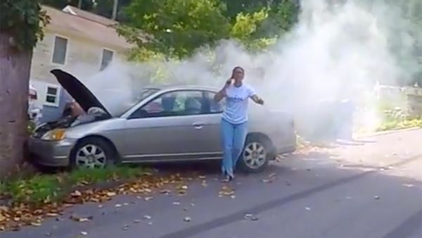 A video showed a woman who appeared to have crashed her car into a tree telling a man careful it's gonna blow and he responded by telling her you can't park your car here ma'am.