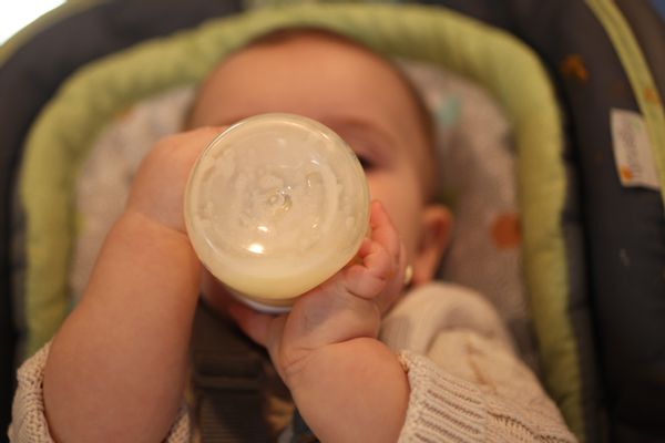 A white baby drinks milk from a bottle.