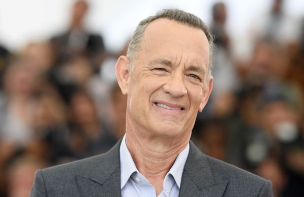 A white man in a gray suit grimaces looking towards the camera.