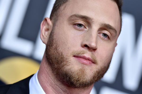 A white man wearing a suit looks towards the camera.