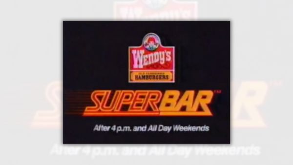 A logo that says "Wendy's Old-Fashioned Hamburgers" below a red-haired girl with pigtails wearing a blue dress is at the top of the image. Below, the word "SuperBar" is in orange and red. "The word "Super" is in red with orange outlining, while the word "Bar" is in orange with red outlining. Both words are underline. At the bottom in white, it says, "After 4 p.m. and All Day Weekends."